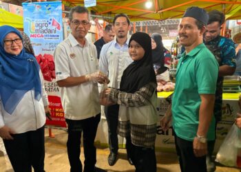 LUQMAN  Ahmad  (dua dari kiri) menyerahkan daging lembu tempatan kepada pengguna dengan harga RM15 sekilogram sempena promosi semasa Program Jualan Agromadani Mega di Pusat Transformasi Luar Bandar (RTC) di Tunjong Kota Bharu, Kelantan. - UTUSAN/ ROSLIZA MOHAMED