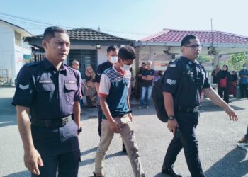 TERTUDUH diiringi polis semasa menghadiri prosiding perbicaraan di  Mahkamah Majistret, Tumpat, Kelantan. - UTUSAN/ROHANA ISMAIL