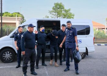 TERTUDUH diiringi polis semasa menghadiri prosiding pertuduhan di Mahkamah Kota Bharu, Kelantan. - UTUSAN/KAMARUL BISMI KAMARUZAMAN