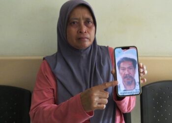 ROPIAH Sari menunjukkan gambar arwah suaminya yang maut dipijak gajah ketika ditemui di Jabatan Forensik Perubatan Hospital Gua Musang, Gua Musang, Kelantan hari ini.