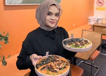 NOOR Ernyza Hanim Mohamad Eljibra menunjukkan menu hidangan Barat yang menjadi pilihan pelanggan di restoran mereka. – MINGGUAN /SAFINA RAMLI