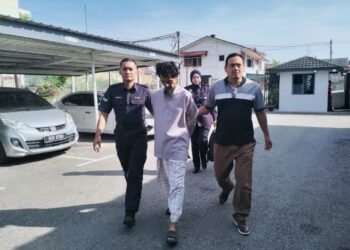 TERTUDUH semasa dibawa polis menghadiri prosiding perbicaraan di Mahkamah Majistret Tumpat, Kelantan. - UTUSAN/ROHANA ISMAIL