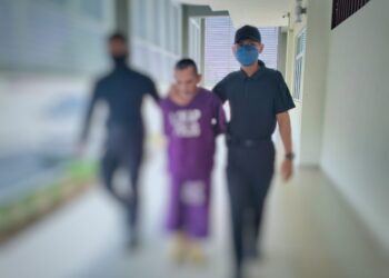 TERTUDUH (tengah) dibawa oleh dua anggota polis untuk mengadiri prosiding perbicaraan di Mahkamah Sesyen Pasir Mas, Kelantan. - UTUSAN/ROHANA ISMAIL
