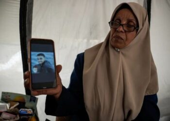 INAAM memegang gambar anak sulungnya yang ditahan oleh Israel, Mahmoud, di khemahnya di Gaza City. 
–  AGENSI