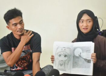 NORASIKIN Hasin dan Muhamad Abdul Hadi Mohd Fauzi  menunjukkan lakaran lukisan ditemukan dalam diari anaknya yang didakwa menjadi mangsa buli di kediamannya di Chuping, Padang Besar, Perlis, semalam.