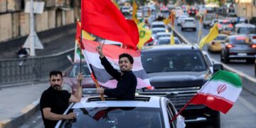 DUA lelaki mengibarkan bendera Iraq, Iran, Lubnan dan Hizbullah di Baghdad, susulan pengumuman perjanjian menamatkan perang antara Iran dan Amerika Syarikat (AS).- AFP