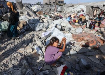 PENDUDUK Palestin mengutip barang keperluan mereka di lokasi serangan udara Israel di kem perlindungan Khan Younis, selatan Semenanjung Gaza.- AFP