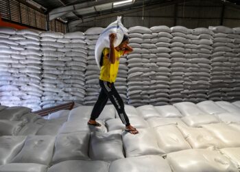 PEKERJA membawa seguni beras di gudang Biro Logistik Indonesia (BULOG) di Lambaro, wilayah Aceh.- AFP