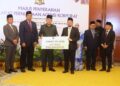 Mustakim Mohamad (depan, kanan) menyerahkan replica cek Zakat TH bagi tahun kewangan 2025 kepada Mohd Ali Mohd Rustam (dua kanan) dalam majlis yang telah berlangsung di Dewan Seri Utama, Pejabat Yang di-Pertua Negeri Melaka.