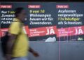 SEORANG lelaki berjalan di hadapan poster kempen inisiatif untuk mengehadkan populasi kepada 10 juta, yang dilancarkan Parti Rakyat Switzerland (SVP) di Zurich.- AFP
