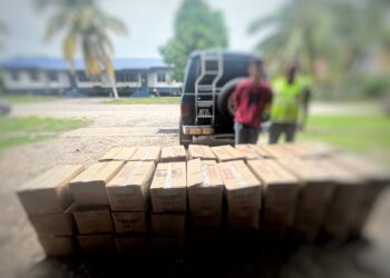 SUSPEK (kiri) bersama kotak minyak masak peket selepas ditahan di Kampung Simpangan, Tumpat, Kelantan.
