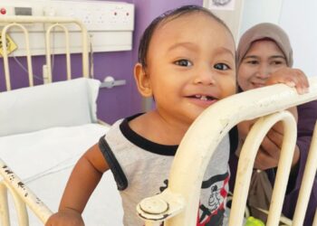 MOHAMAD Yafiy Darwish Mohamad Faizal tersenyum riang sambil diperhatikan ibunya, Mashitoh Mat Isa (belakang) ketika dirawat di sebuah hospital di Pulau Pinang, baru-baru ini.