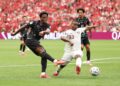 PEMYERANG Kanada, Jonathan David (kiri) melakukan rembatan kencang ke gawang Qatar sambil cuba dihadang pertananan lawan pada aksi kedua Kumpulan B di Stadium BC Place sebentar tadi.-AFP