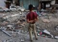 SEORANG kanak-kanak lelaki Palestin melihat runtuhan bangunan kediaman dan sebuah kereta yang rosak selepas serangan Israel di Bandar Gaza hari ini. - AFP