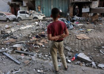 SEORANG kanak-kanak lelaki Palestin melihat runtuhan bangunan kediaman dan sebuah kereta yang rosak selepas serangan Israel di Bandar Gaza hari ini. - AFP
