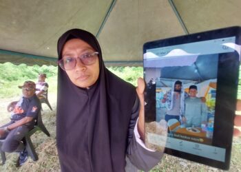 NORMAZITA Ishury menunjukkan gambar Samsul Azmi (kiri dalam gambar) yang hilang dikhuatiri lemas di Sungai Pahang dekat Kampung Peragap di Temerloh, Pahang.