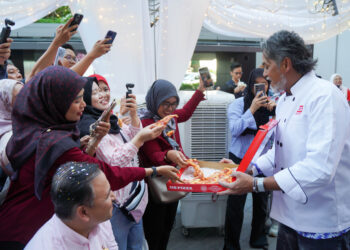 KHAIRY Jamaluddin mengagihkan pizza percuma kepada pengunjung sempena majlis pengiktirafan US Pizza oleh Malaysia Book of Records di DPULZE Shopping Centre, Cyberjaya.