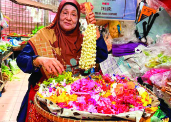 AZIZAH Mohd. Nor menunjukkan pelbagai jenis bunga yang dijual kepada pelanggan di Pasar Siti Khadijah Kota Bharu, Kelantan. - UTUSAN/ ROSLIZA MOHAMED