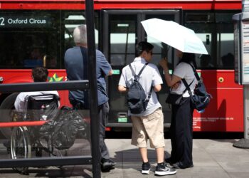 SEORANG wanita menggunakan payung ketika cuaca panas di London. - AFP
