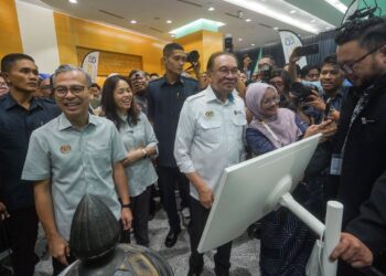 ANWAR Ibrahim diiringi Fahmi Fadzil melawat pameran selepas Perjumpaan Bulanan Kementerian Komunikasi di Putrajaya, semalam. – UTUSAN/FAISOL MUSTAFA
