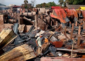 SEORANG mangsa kebakaran berjalan di atas runtuhan bumbung rumah yang hangus dalam kebakaran yang memusnahkan 29 buah rumah di Kampung Gok Kapur, Kota Bharu, semalam. – UTUSAN/KAMARUL BISMI KAMARUZAMAN
