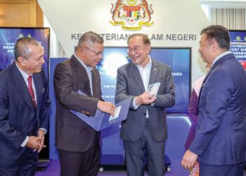 ANWAR IBRAHIM merasmikan pasport Malaysia Antarabangsa baharu sambil disaksikan Zakaria Shaaban (kanan) dan Menteri Dalam Negeri, Datuk Seri Saifuddin Nasution Ismail di Parlimen, semalam.  – UTUSAN/FARIZ RUSADIO