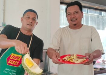 SHIK Khalil Abd Karim (kiri) menunjukkan durian musang king premium dari Raub yang menjadi ramuan utama menu unik roti canai yang dijual pada harga RM5 sekeping di Bagan Serai. - UTUSAN/WAT KAMAL ABAS