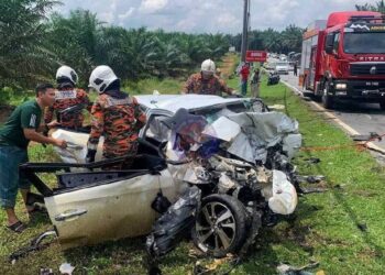 BEBERAPA anggota bomba membantu mengeluarkan mangsa kemalangan di Jalan Renggam-Simpang Renggam, hadapan Penjara Simpang Renggam tengah hari tadi. - IHSAN JBPM