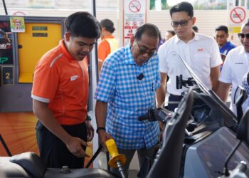 MOHAMED KHALED Nordin (tengah) membantu pengunjung mengisi minyak pada program Pengisian Minyak Percuma Untuk Motosikal di BHP Felda Ayer Tawar 2, Kota Tinggi.