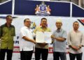 MOHD. Hairi Mad Shah (tengah) menyaksikan Pentadbir Tanah Johor Bahru Syed Norul Shahril Syed Nasir (dua dari kiri) menyerahkan Notis 5A kepada salah seorang penduduk pada Majlis Penyerahan Notis 5A Permohonan Perbaharui Tempoh Pajakan kepada penduduk Kampung Melayu Majidi di Medan Niaga Kampung Melayu Majidi, Johor Bahru disini. UTUSAN/RAJA JAAFAR ALI