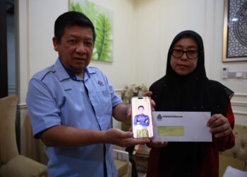 SHARULANUAR Baharom (kiri) bersama isteri menunjukkan gambar anaknya, Muhammad Amirul Jaris yang mendermakan kornea matanya selepas maut dalam kemalangan semasa menerima kunjungan Perkeso di Lorong Kubor, Taman Mekasar, Kampung Kasar, Pasir Mas, Kelantan-UTUSAN/KAMARUL BISMI KAMARUZAMAN.