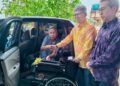 RAJA Nurshirwan Zainal Abidin menyerahkan kerusi roda kepada seorang penerima di pekarangan Wat Machimmaram Jubakar Tumpat, Kelantan. - UTUSAN/ ROHANA ISMAIL