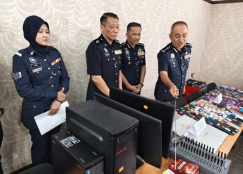 MOHD. Alwi Zainal Abidin (kanan) menunjukkan barangan yang dirampas selepas menahan tiga individu yang dipercayai membekalkan telefon bimbit dan kad sim kepada sindiket penipuan dalam talian di Bandar Baru Medan, Ipoh minggu lalu.