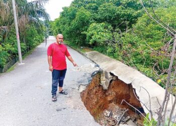 MD. Rosli Ibrahim menunjukkan tanah runtuh dan kesan jerlus yang didakwa terbiar sejak lebih tiga bulan lalu di Jalan Kelisa Ria 5, Taman Kelisa di Sungai Petani.