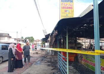 ROHAMI Mohd. (kanan) melihat keadaan kedai keropoknya yang musnah dalam kebakaran i di Kampung Losong Haji Su, Kuala Terengganu, Terengganu. - UTUSAN/ERMA YUSNIDA JUSOH