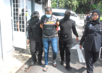 TERTUDUH, P. Kogilanathan diiringi polis dibawa keluar dari Mahkamah Jasin hari ini selepas dituduh membunuh seorang peniaga dua tahun lalu. UTUSAN/AMRAN MULUP