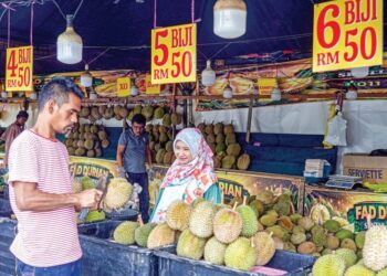 PEKERJA kedai durian menunjukkan isi durian kepada pelanggan ketika tinjauan Utusan Malaysia di sebuah gerai durian di sekitar Sentul, semalam. – UTUSAN/ISKANDAR ISHAK