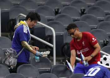 PENYOKONG Jepun meneruskan amalan murni mereka dengan membersihkan kawasan tempat duduk usai tamat perlawanan. - AFP
