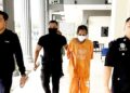 TERTUDUH diiringi polis semasa prosiding perbicaraan di Mahkamah Sesyen Pasir Mas, Kelantan.