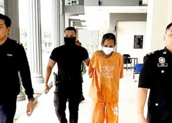 TERTUDUH diiringi polis semasa prosiding perbicaraan di Mahkamah Sesyen Pasir Mas, Kelantan.