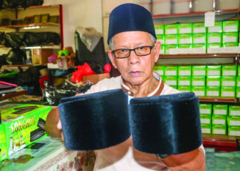 AKMAR Abdul Muluk menunjukkan produk songkok yang dihasilkan di bengkelnya di Felda Semarak Jengka 15 di Maran, Pahang. - UTUSAN/SALEHUDIN MAT RASAD