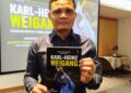 ZUBIR Shaharani menunjukkan buku yang ditulisnya mengenai jurulatih legenda Perak, mendiang Karl-Heinz Weigang dalam majlis pelancaran buku itu di Ipoh, Perak hari ini. - UTUSAN/FADZIL ZAINOL