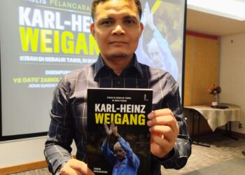 ZUBIR Shaharani menunjukkan buku yang ditulisnya mengenai jurulatih legenda Perak, mendiang Karl-Heinz Weigang dalam majlis pelancaran buku itu di Ipoh, Perak hari ini. - UTUSAN/FADZIL ZAINOL