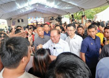 ANWAR Ibrahim menyantuni orang ramai yang hadir Program Kita GenK Madani X Anak Muda Bukit Batu, Kulai, semalam. – MINGGUAN/RAJA JAAFAR ALI