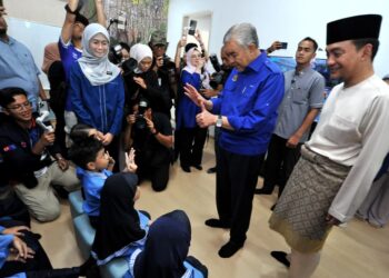 AHMAD Zahid Hamidi menyantuni murid-murid tabika sambil diperhatikan Onn Hafiz pada Majlis Libat Urus Kepimpinan Bersama Ibu Bapa Tabika Kemas Bangsa Johor di Flat Perumahan Larkin Court 1, Larkin Jaya, Johor Bahru, hari ini. - UTUSAN/RAJA JAAFAR ALI