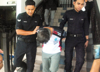 Tertuduh , Mohd. Nizam Ab. Manaf dibawa keluar diiringi anggota polis di Mahkamah Majistret Ayer Keroh hari ini. UTUSAN/AMRAN MULUP