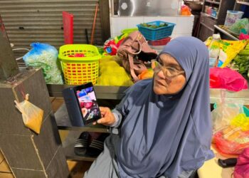 JAMALIAH YUSOFF menunjukkan gambar gerai ketika banjir di Medan Selera Seksyen 51A atau Medan Selera 223, Petaling Jaya, semalam.