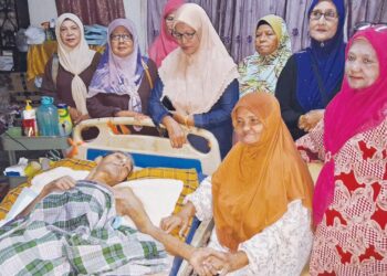 MASLAMAH Sani memegang tangan suaminya yang terlantar semasa dikunjungi rombongan Persatuan Sahabat 60-an Jengka Maran di Felda Jengka 5, Maran, Pahang. – UTUSAN/ SALEHUDIN MAT RASAD