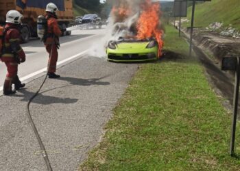 ANGGOTA bomba memadamkan kebakaran membabitkan kereta jenis Porsche 718 Clayman GTS di Kilometer 348, Lebuh Raya Utara-Selatan menghala Selatan Sungkai, Bidor, Tanjung Malim, hari ini. - FOTO IHSAN JBPM PERAK