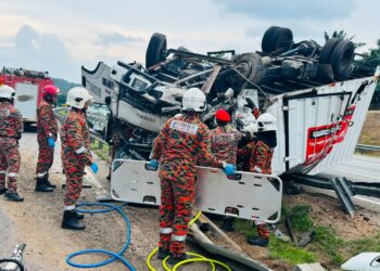 ANGGOTA bomba cuba mengeluarkan pemandu lori berusia 40-an yang tersepit di tempat duduk dalam kemalangan yang berlaku berhampiran Plaza Tol Simpang Ampat arah utara hari ini. - FOTO IHSAN JBPM MELAKA.